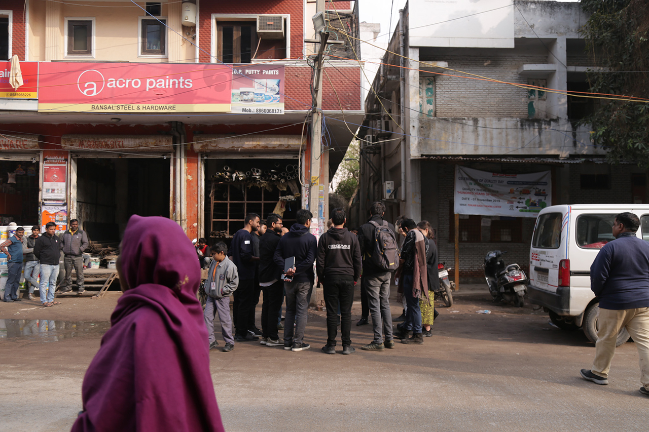 A group of people from our workshop group is standing in a circle in a Delhi street and discussing internet infrastructure. People around us gaze seem interested and look at us.
