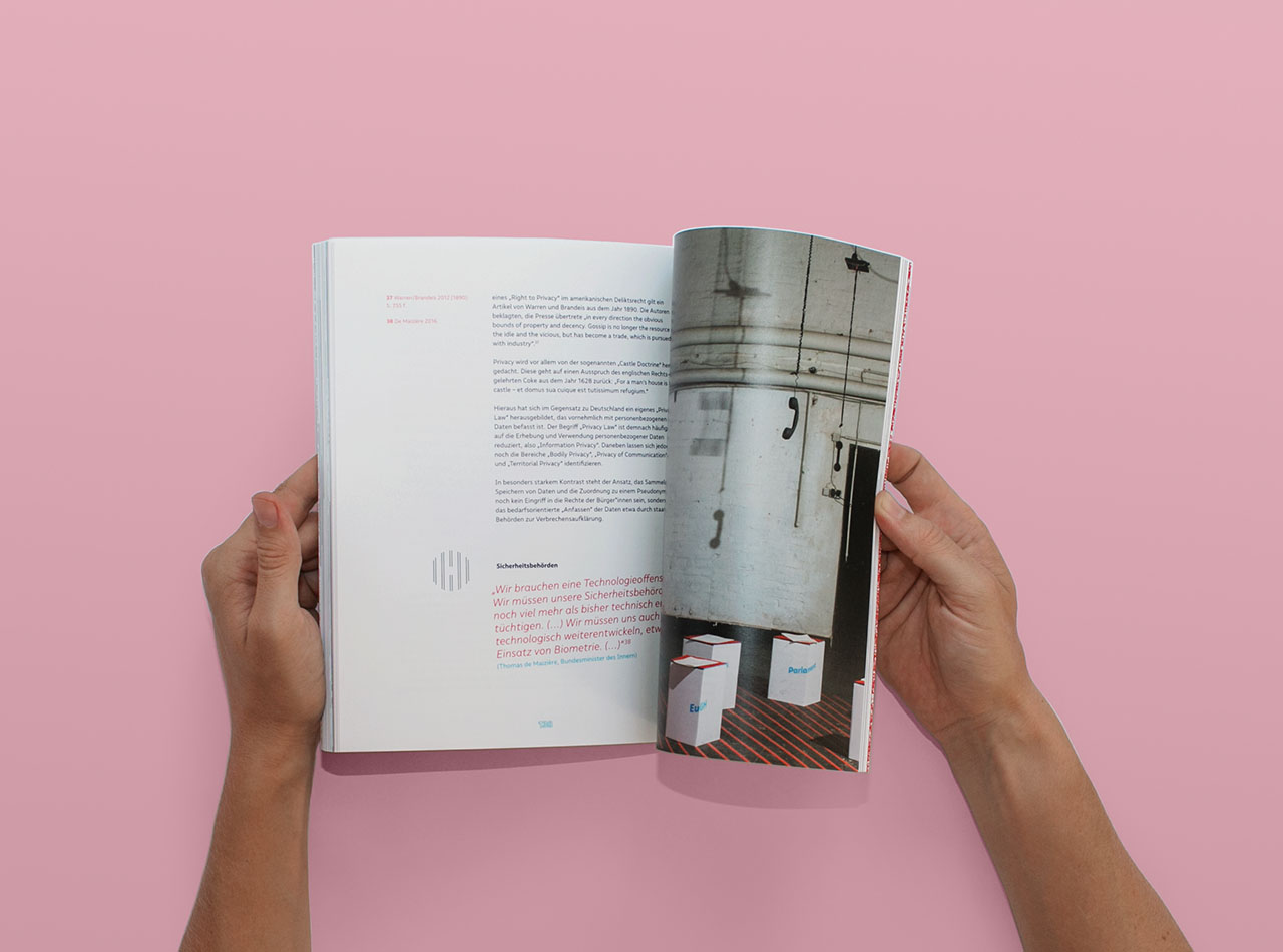 Two hands open the book Privacy Arena. The open pages show a photo of the exhibition, and text.