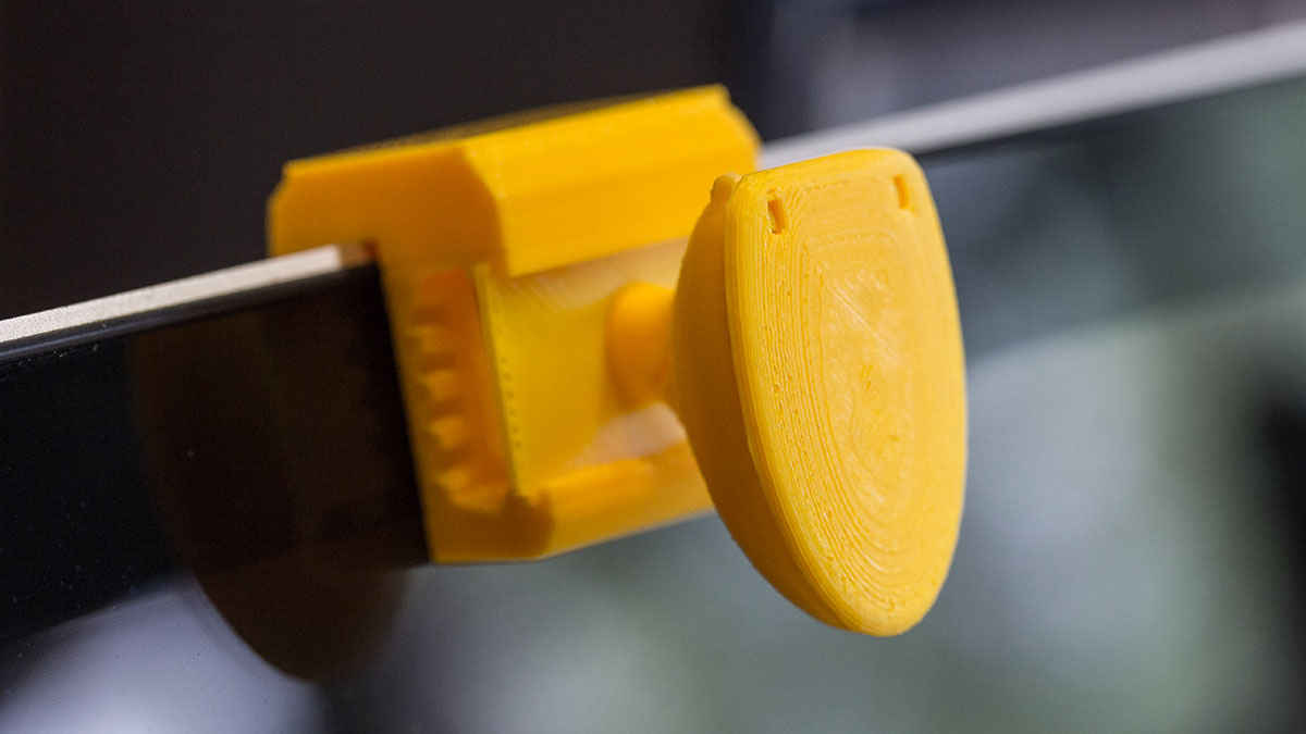 A 3D printed toilet sits atop the built-in webcamera of a macbook. The lid of the toilet is closed.